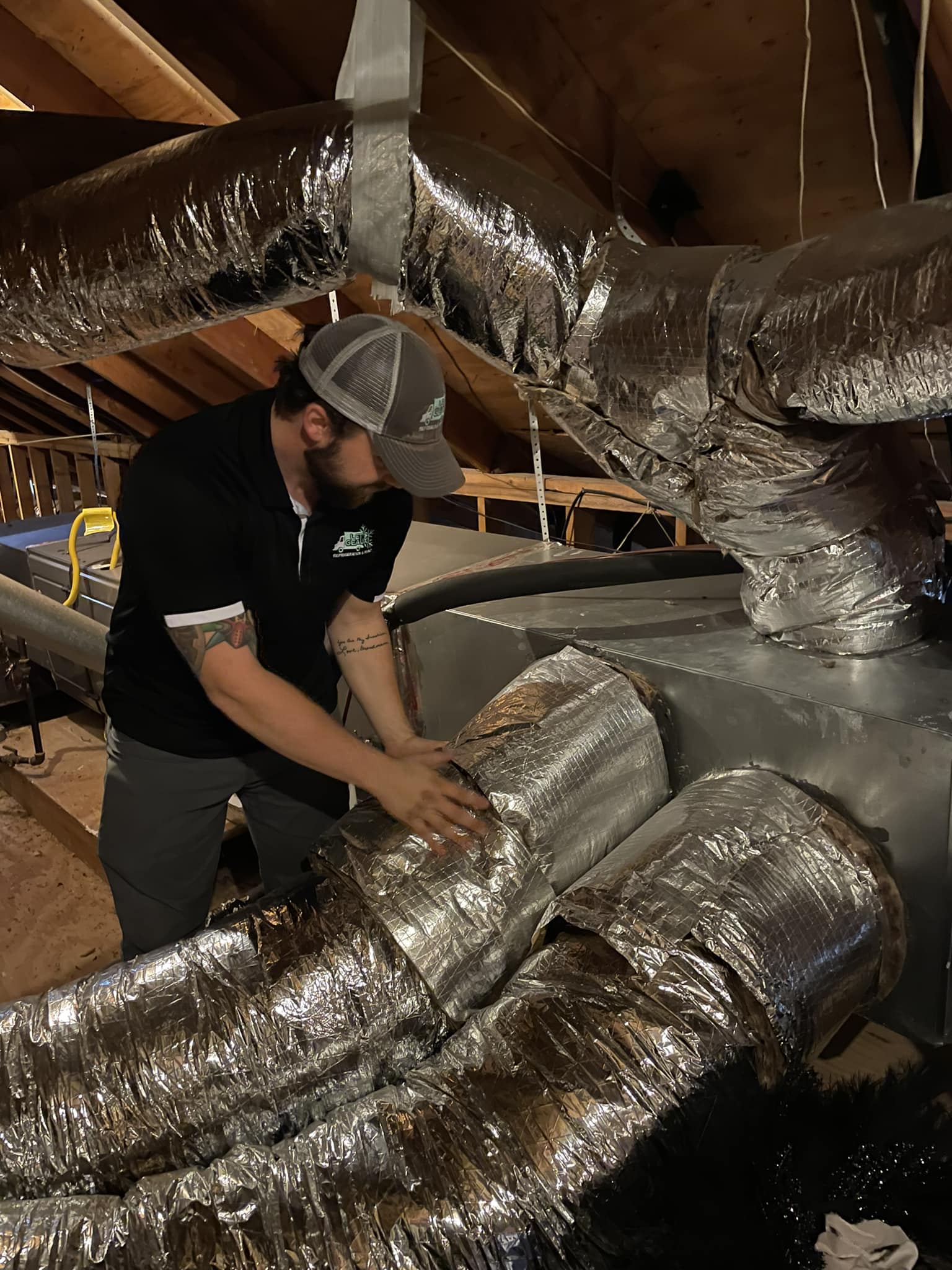 Technician inspecting or installing ductwork in an attic