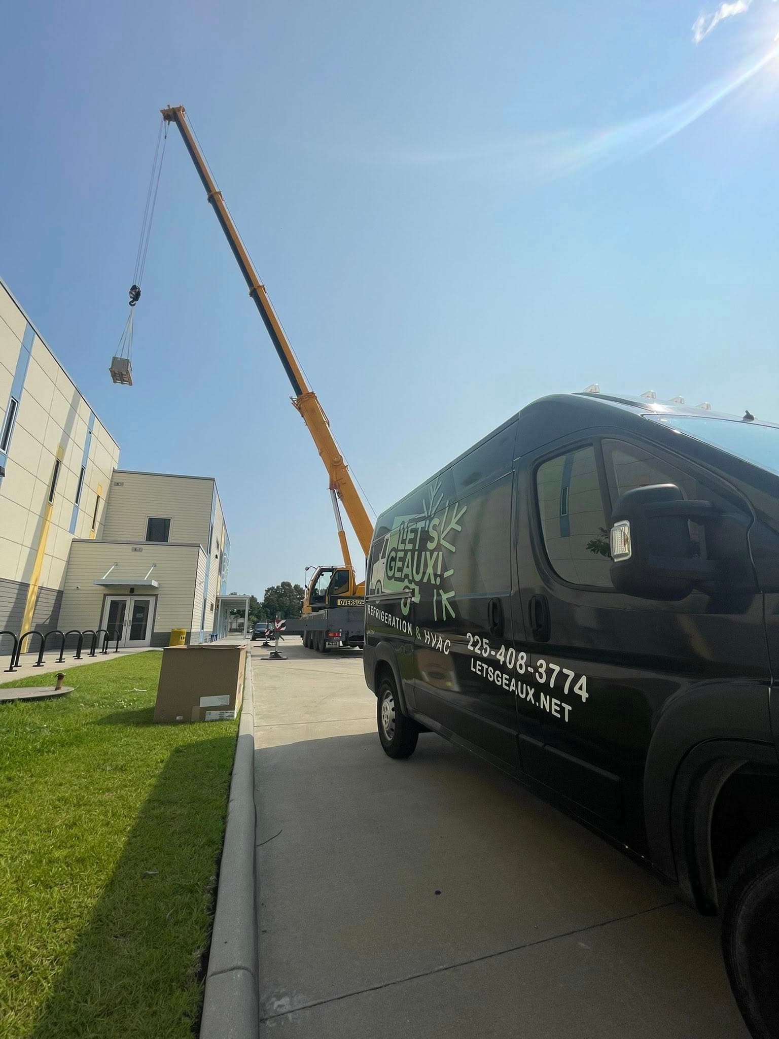 Branded service van and crane at a job site