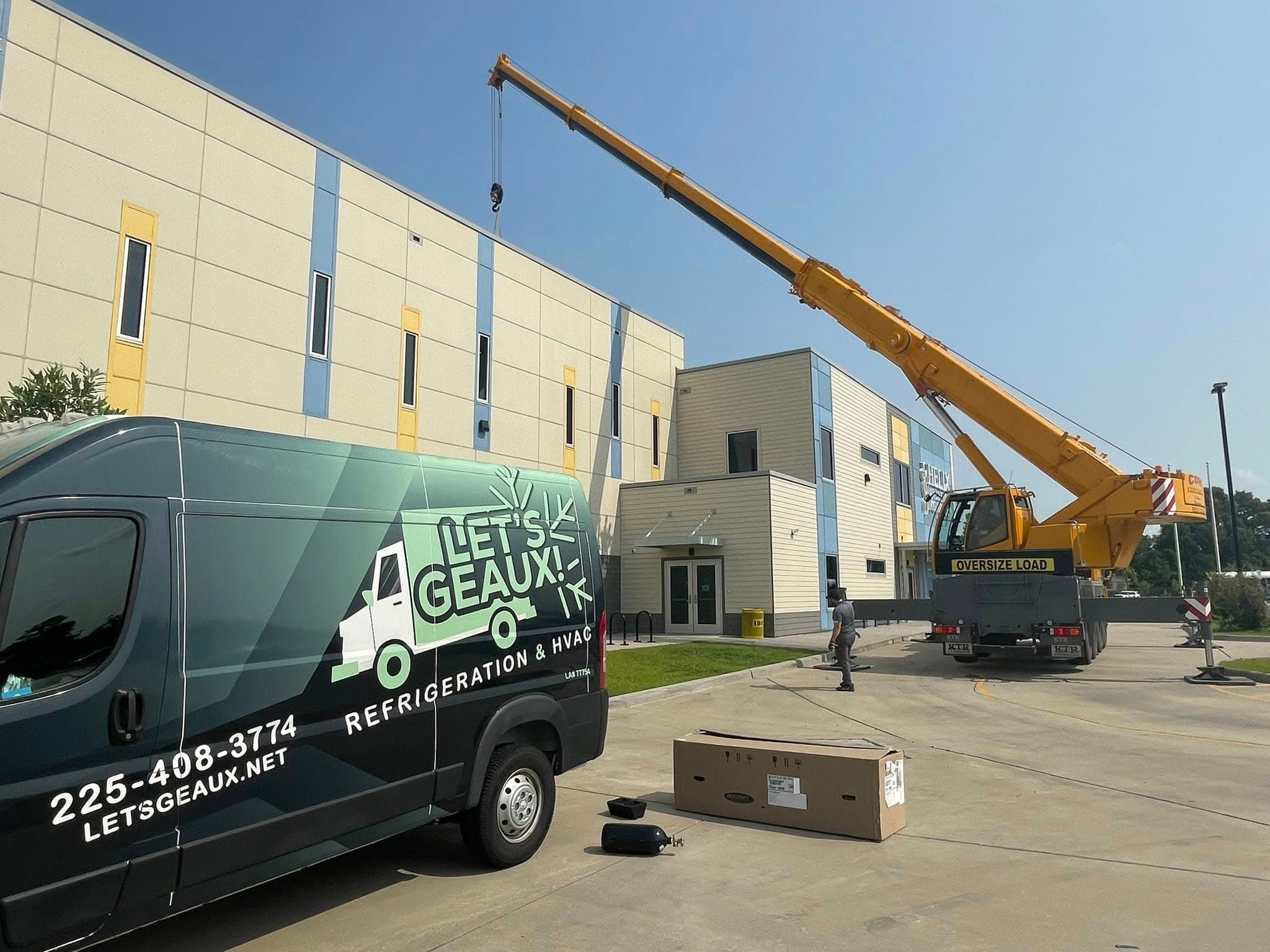 Service van and crane at a commercial HVAC job site