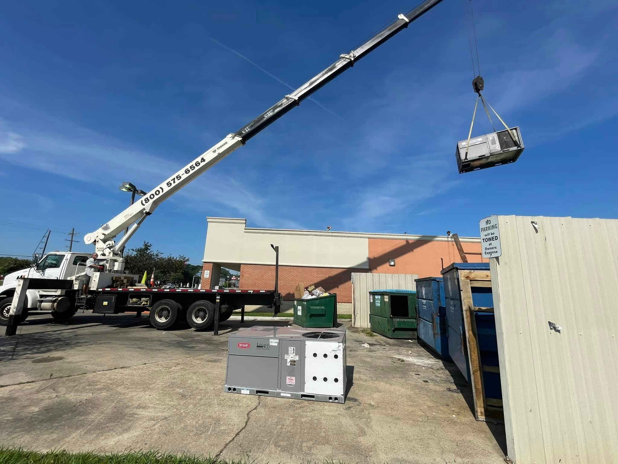 Crane placing a commercial rooftop HVAC unit