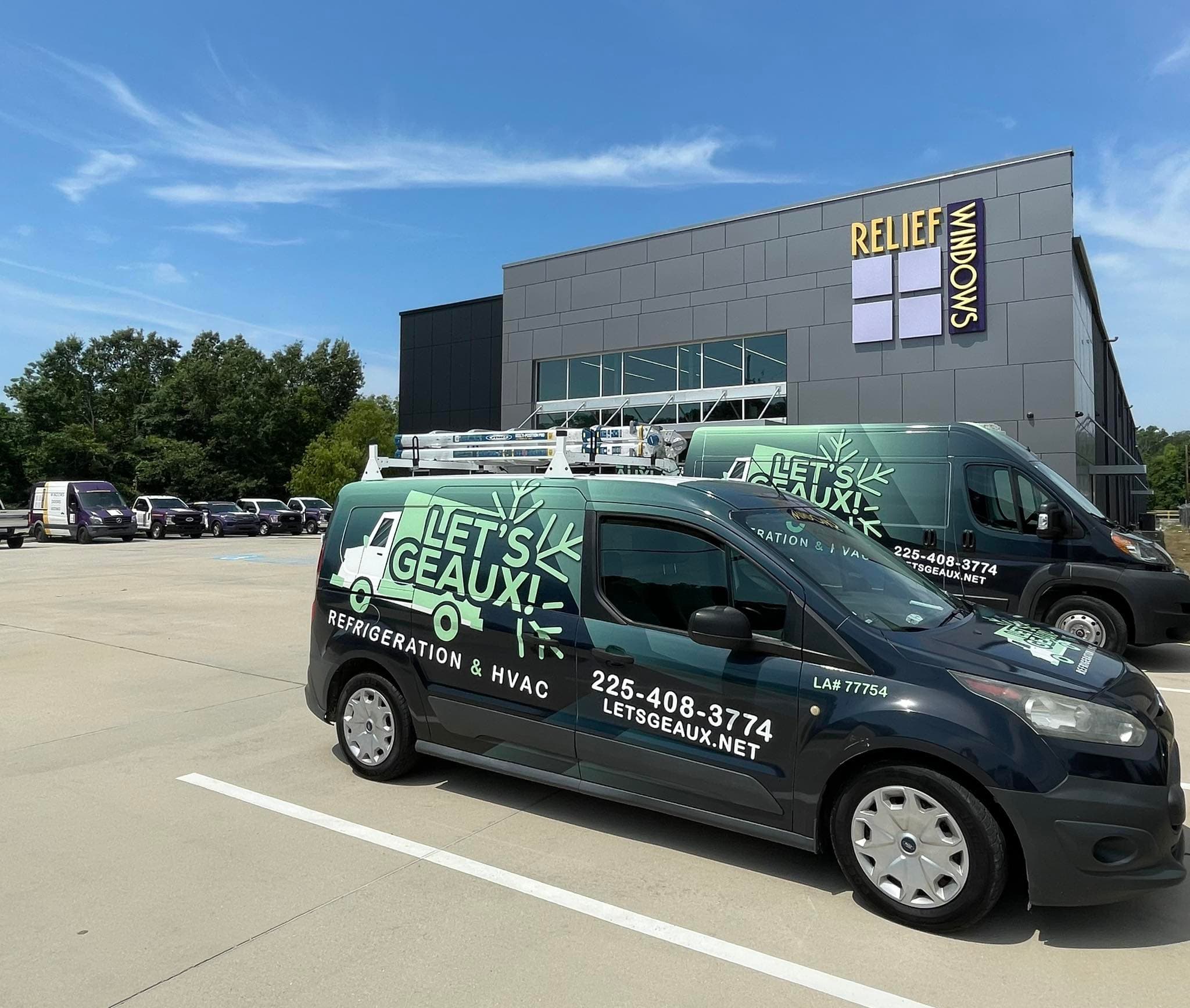 Two Let's Geaux branded service vans at a commercial property